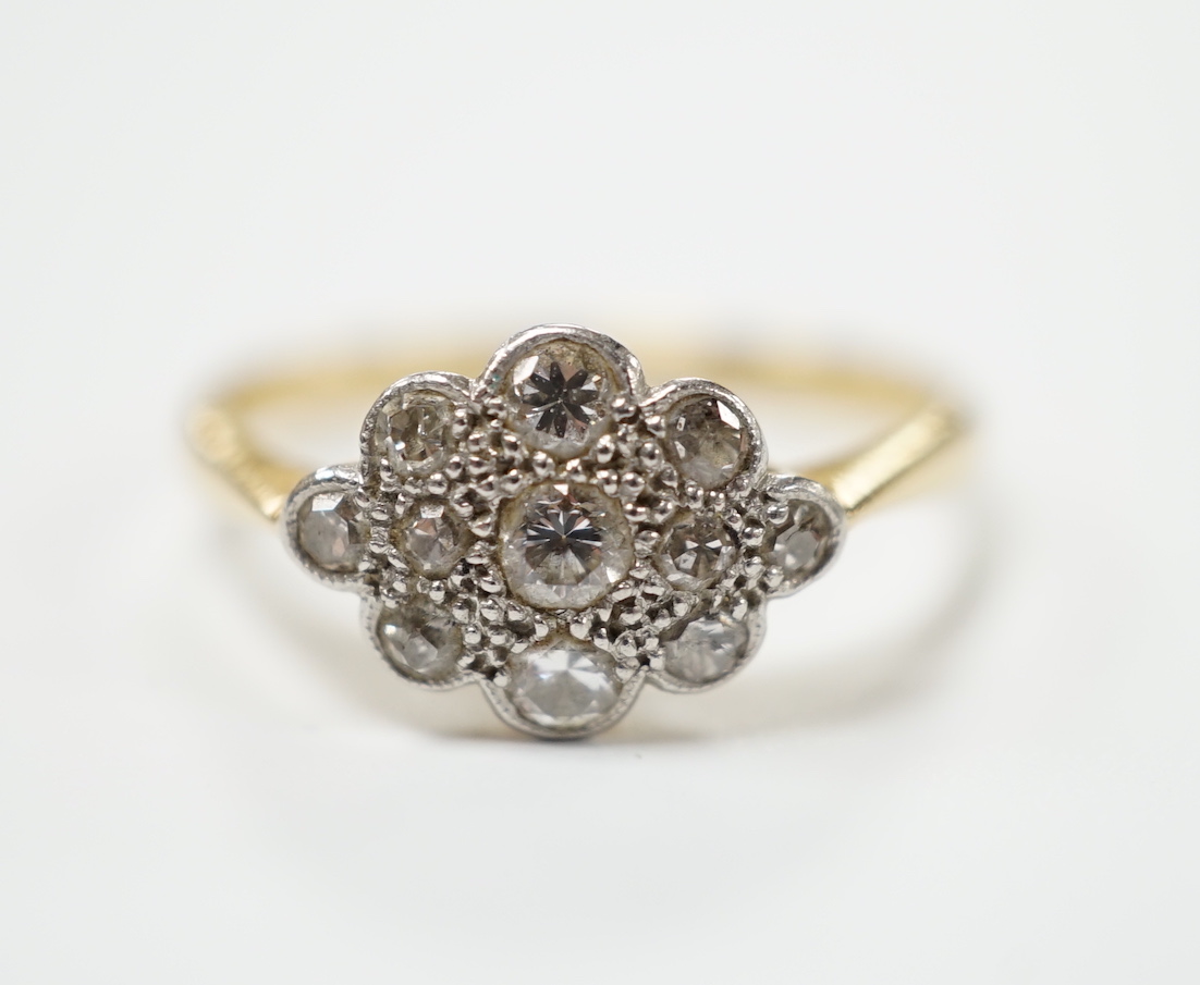 A 1920's 18ct, plat and millegrain set diamond cluster ring, size P, gross weight 3 grams.
